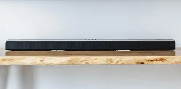 Aflang, sort soundbar placeret på mediemøbel i eg