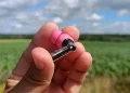 Anmelder holder en rosa Nothing Ear (3a)-høretelefon i sin hånd med mark i baggrunden
