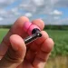 Anmelder holder en rosa Nothing Ear (3a)-høretelefon i sin hånd med mark i baggrunden