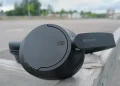 Sorte Sony WH-CH720N placeret på trægelænder med parkeringspladser i baggrunden