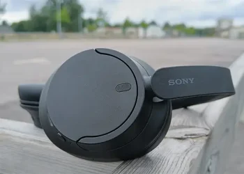 Sorte Sony WH-CH720N placeret på trægelænder med parkeringspladser i baggrunden