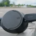 Sorte Sony WH-CH720N placeret på trægelænder med parkeringspladser i baggrunden