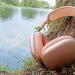 Apple AirPods Max 2 Orange lænet mod en træstamme med en å i baggrunden